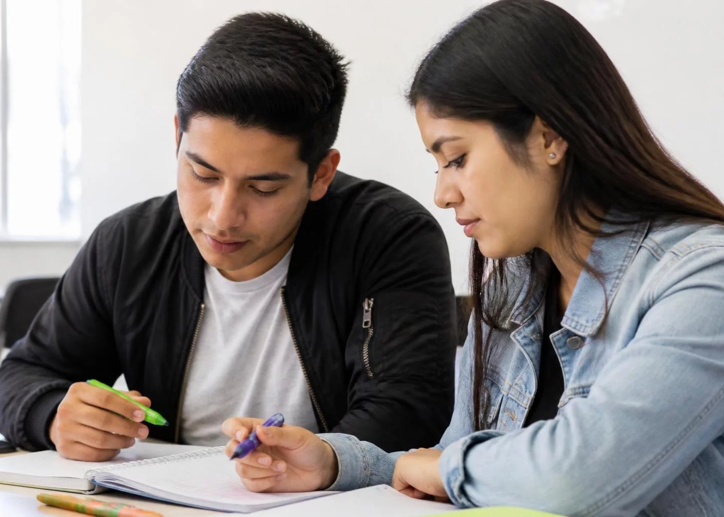 Dos participantes trabajando juntos con cuaderno y plumones